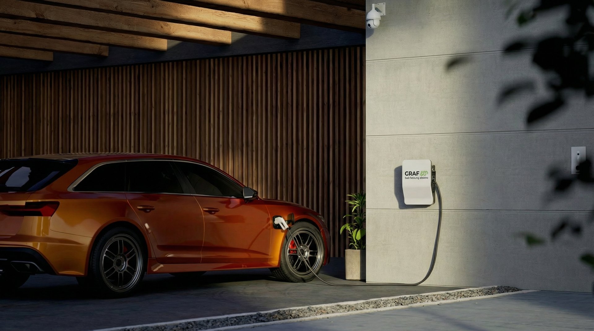 Ein orangefarbener Audi Kombi wird in einem modernen Carport an einer GRAF Wallbox geladen. Die Wallbox ist an einer grauen Betonwand befestigt, daneben steht eine grüne Pflanze. Im Hintergrund sind eine Holzlamellenwand und Holzbalken an der Decke sichtbar. Eine Überwachungskamera ist ebenfalls an der Wand installiert. Ladeinfrastruktur von Graf Gmbh aus Kandern.